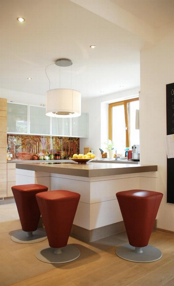 Foto di una cucina ad U design con ante lisce, ante in legno chiaro, pavimento in legno massello medio, penisola, paraspruzzi multicolore e paraspruzzi con lastra di vetro