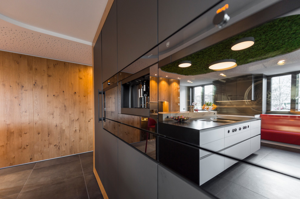 Design ideas for an expansive contemporary l-shaped enclosed kitchen in Other with flat-panel cabinets, grey cabinets, black appliances, an island and grey floors.