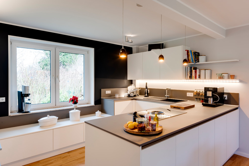 Foto på ett mellanstort funkis grå u-kök, med en nedsänkt diskho, släta luckor, vita skåp, bänkskiva i koppar, en halv köksö, brunt golv och mellanmörkt trägolv