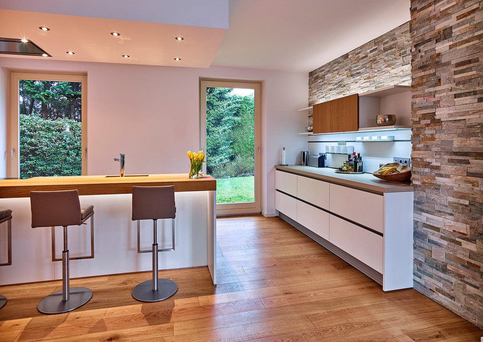 Foto di una grande cucina design con ante lisce, ante bianche e pavimento in legno massello medio