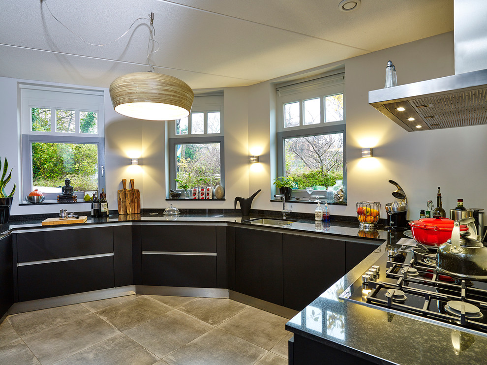 This is an example of a large contemporary u-shaped enclosed kitchen in Other with a built-in sink, flat-panel cabinets, black cabinets, granite worktops, black appliances, terracotta flooring and no island.