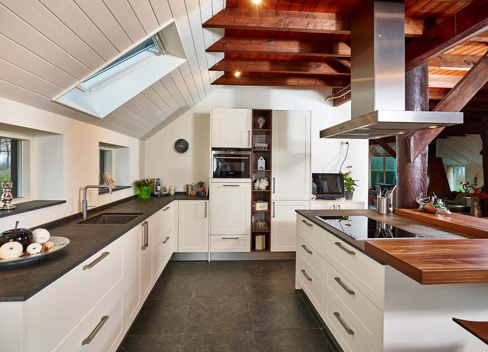 Bild på ett lantligt kök, med en undermonterad diskho, skåp i shakerstil, vita skåp, en köksö, vitt stänkskydd, bänkskiva i kvarts, vita vitvaror och betonggolv