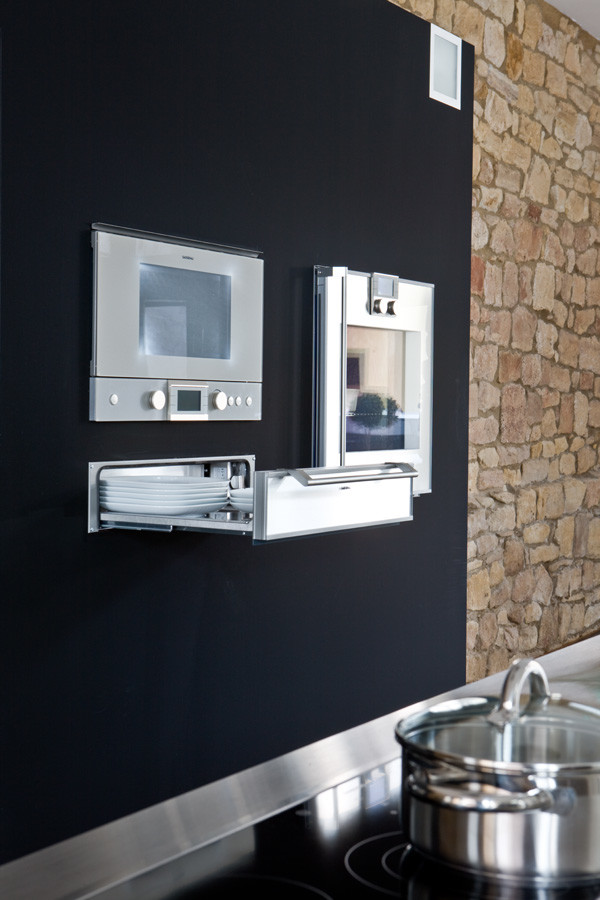 Foto di un'ampia cucina minimal con lavello a vasca singola, ante nere, top in acciaio inossidabile e elettrodomestici in acciaio inossidabile