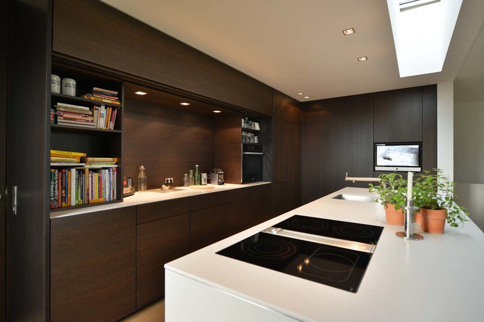 Moderne Küche in L-Form mit flächenbündigen Schrankfronten, dunklen Holzschränken, Kücheninsel und Unterbauwaschbecken in Düsseldorf