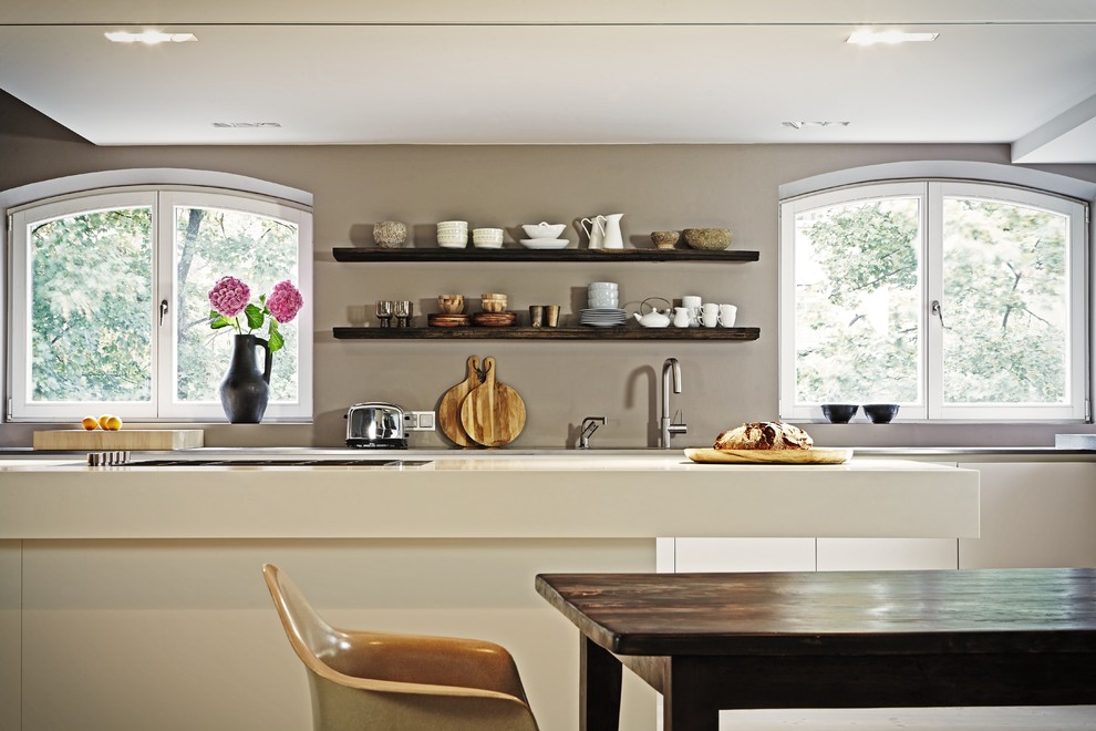 Пример оригинального дизайна: кухня в современном стиле с обеденным столом, плоскими фасадами, белыми фасадами и островом