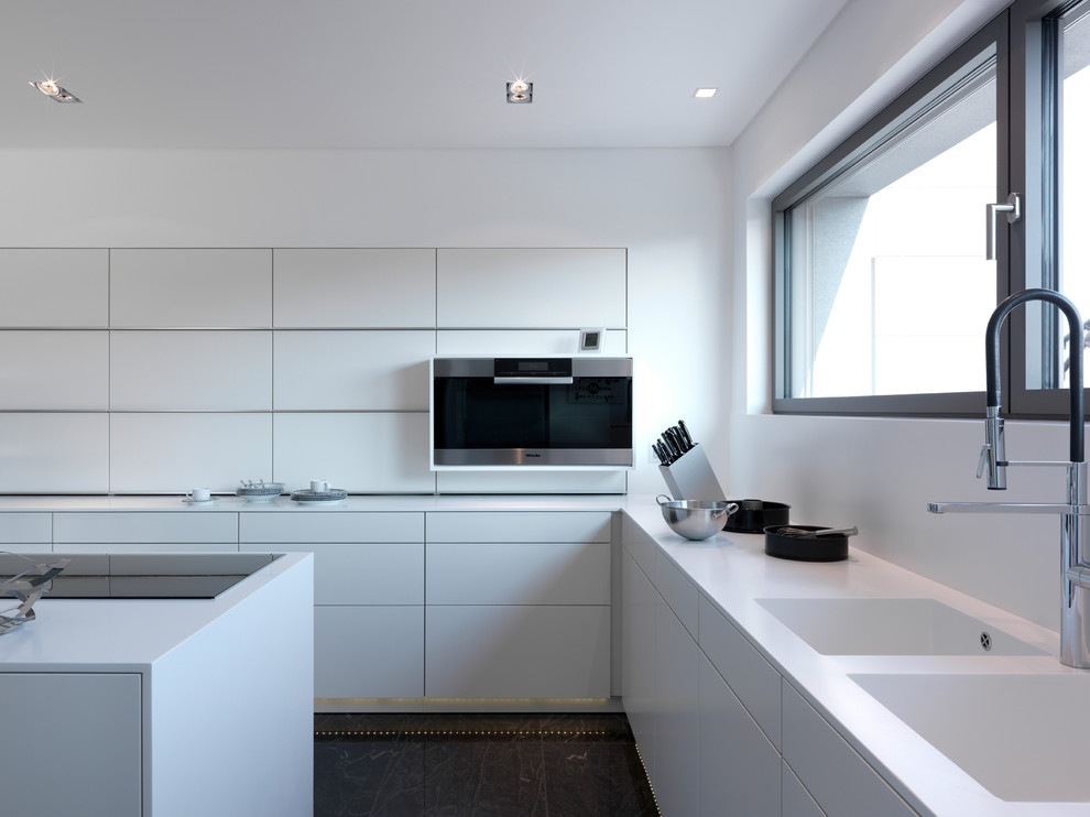 Modern inredning av ett avskilt, stort l-kök, med släta luckor, vita skåp, en dubbel diskho, integrerade vitvaror, skiffergolv och en köksö