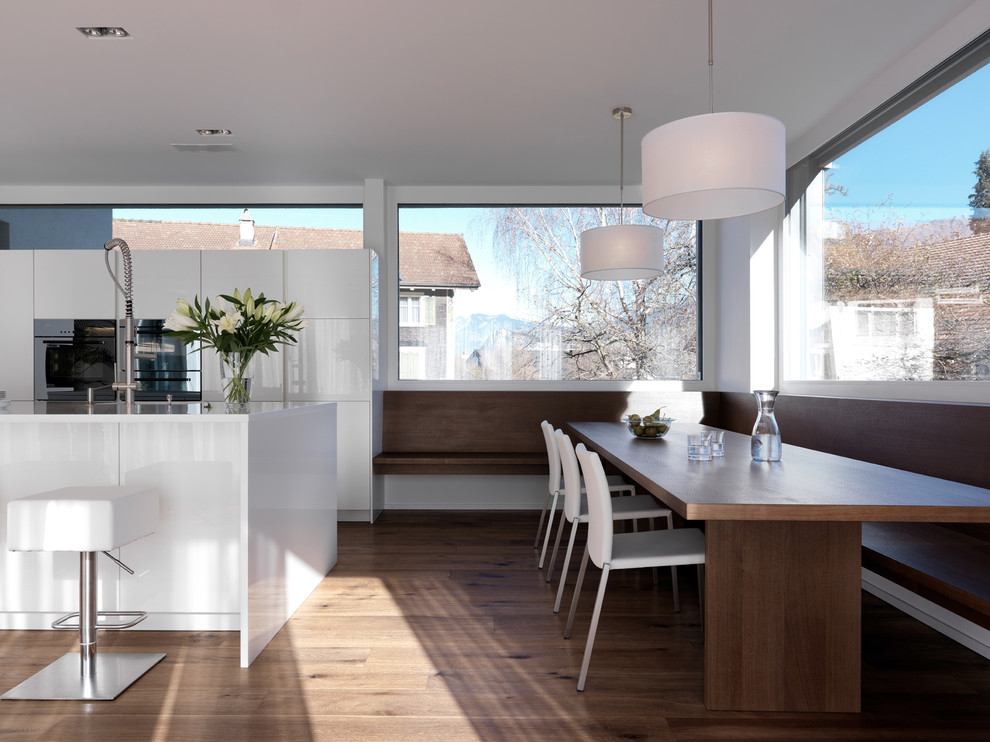 Photo of a large modern kitchen/diner in Stuttgart with flat-panel cabinets, white cabinets, dark hardwood flooring, an island and stainless steel appliances.