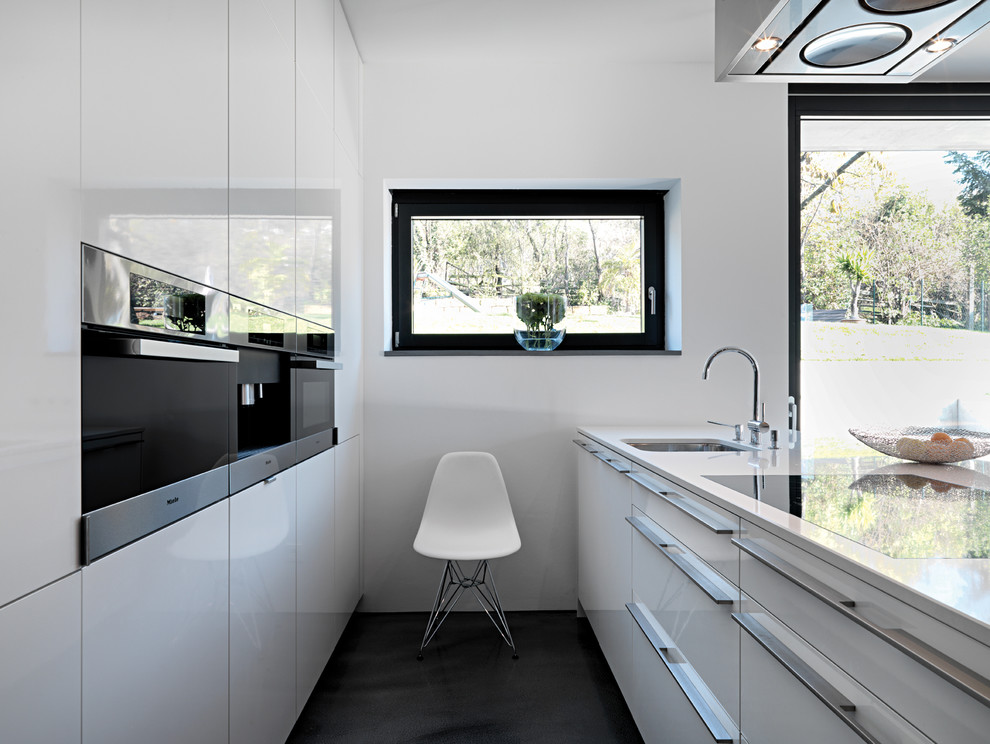 Diseño de cocina moderna con fregadero bajoencimera, armarios con paneles lisos, puertas de armario blancas, electrodomésticos con paneles y península