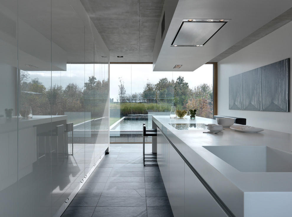 Inspiration for a large contemporary enclosed kitchen in Stuttgart with an integrated sink, flat-panel cabinets, white cabinets, integrated appliances, slate flooring and an island.