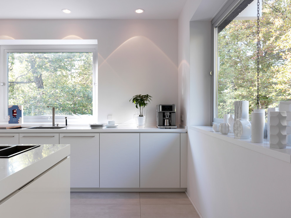 Moderne Küche mit Unterbauwaschbecken, flächenbündigen Schrankfronten, weißen Schränken und Elektrogeräten mit Frontblende in Stuttgart