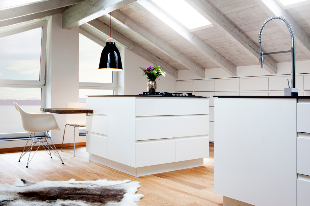 ミュンヘンにあるラグジュアリーな広い北欧スタイルのおしゃれなキッチン (フラットパネル扉のキャビネット、白いキャビネット、淡色無垢フローリング、一体型シンク、人工大理石カウンター、白いキッチンパネル、木材のキッチンパネル、パネルと同色の調理設備、茶色い床) の写真