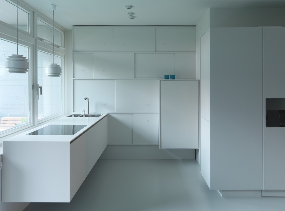 Foto på ett mellanstort funkis kök och matrum, med en integrerad diskho, vita skåp, svarta vitvaror, linoleumgolv, vitt golv och släta luckor