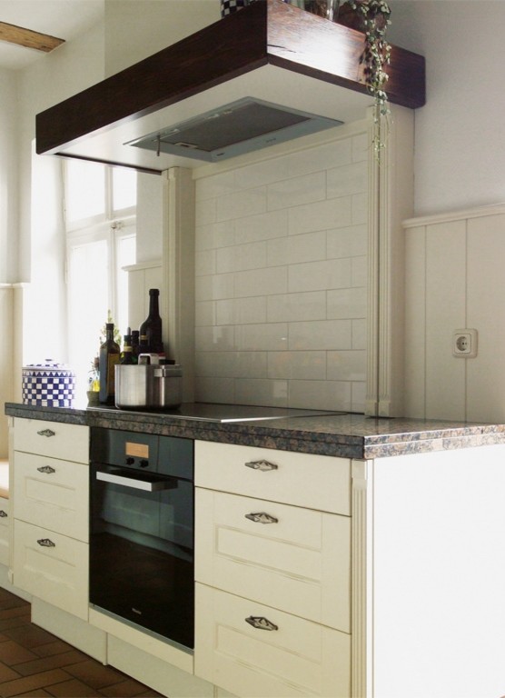 Foto på ett litet lantligt kök, med en rustik diskho, luckor med profilerade fronter, vita skåp, granitbänkskiva, vitt stänkskydd, stänkskydd i keramik, svarta vitvaror och klinkergolv i terrakotta