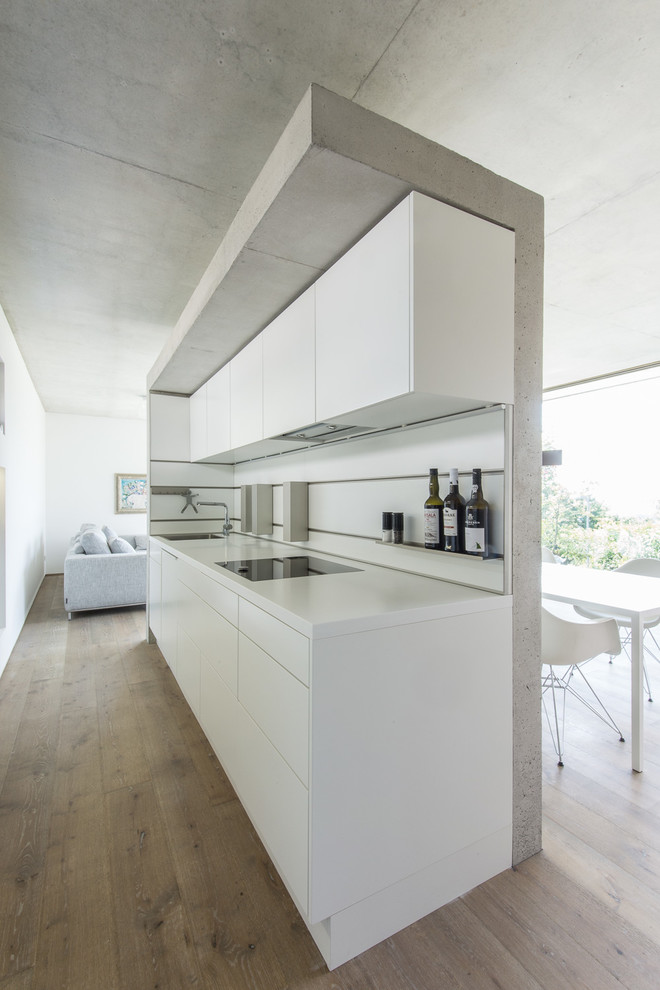 Exemple d'une petite cuisine ouverte linéaire moderne avec un placard à porte plane, des portes de placard blanches, une crédence blanche, parquet foncé et aucun îlot.