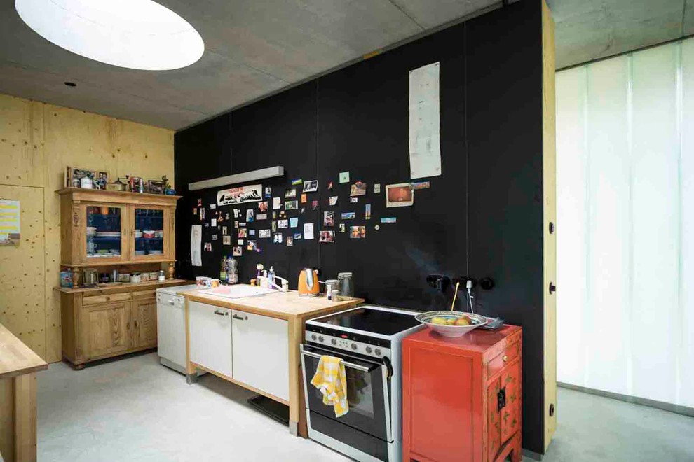 Cette photo montre une cuisine éclectique de taille moyenne avec un évier posé, une crédence noire et sol en béton ciré.