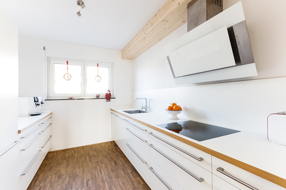 Geschlossene, Zweizeilige, Kleine Klassische Küche ohne Insel mit weißen Schränken, Küchenrückwand in Weiß, braunem Holzboden, braunem Boden und weißer Arbeitsplatte in Stuttgart