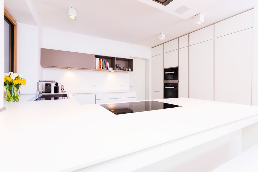 Modern inredning av ett mellanstort kök, med en nedsänkt diskho, släta luckor, vita skåp, vitt stänkskydd, glaspanel som stänkskydd, rostfria vitvaror, ljust trägolv och en halv köksö