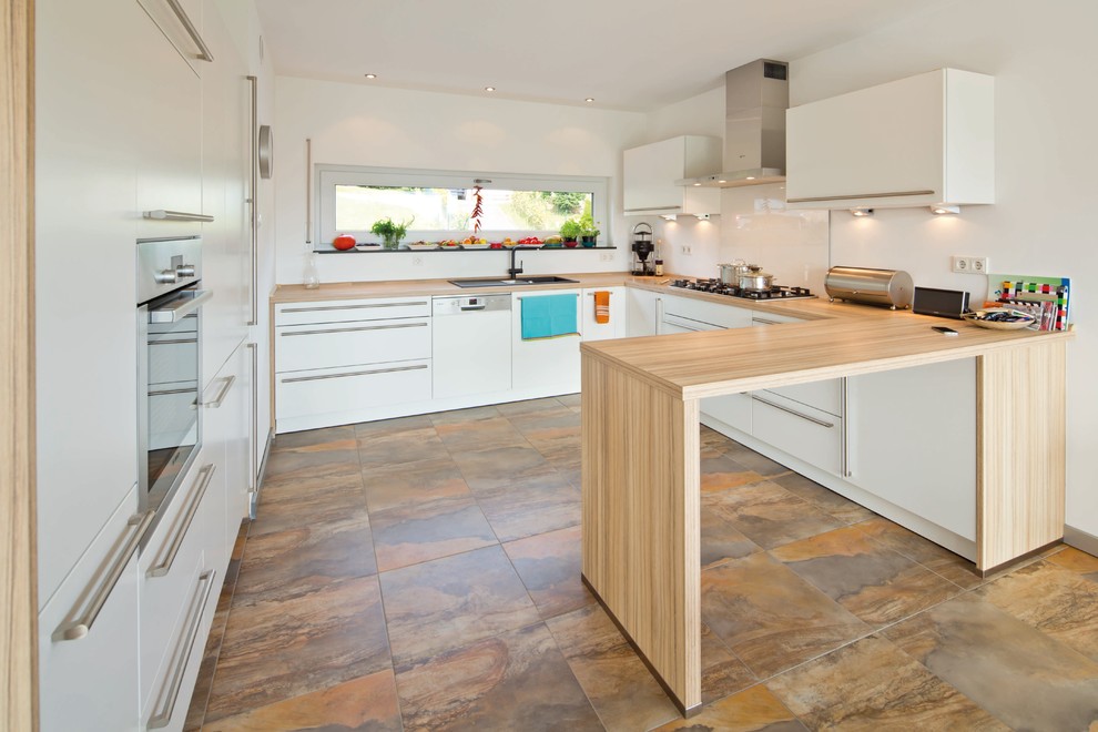 Example of a trendy terra-cotta tile and brown floor kitchen design in Other with a drop-in sink, white cabinets, wood countertops, white backsplash, stainless steel appliances, no island and brown countertops