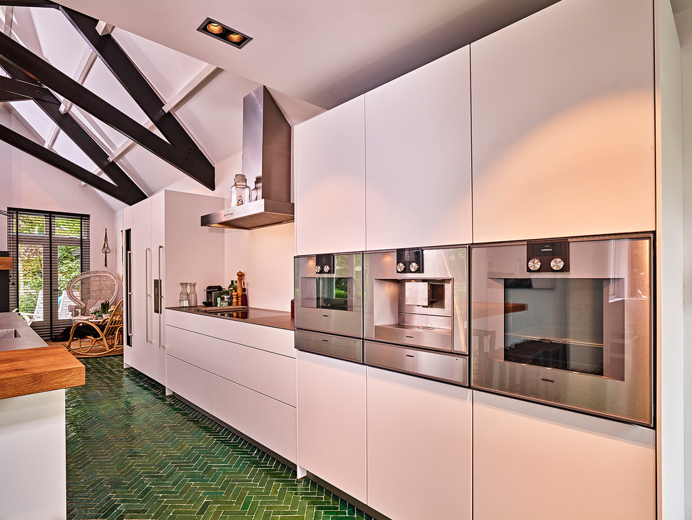 Idéer för att renovera ett mycket stort funkis kök, med en integrerad diskho, släta luckor, vita skåp, bänkskiva i rostfritt stål, vitt stänkskydd, rostfria vitvaror, klinkergolv i keramik, en köksö och grönt golv