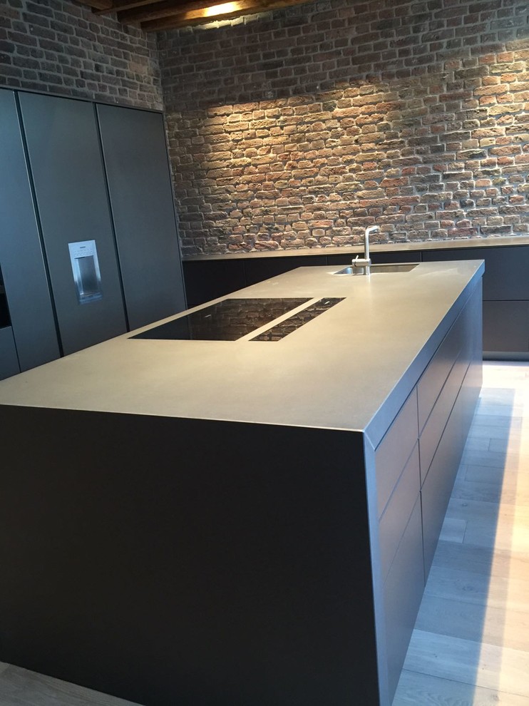 Exempel på ett stort modernt kök, med en integrerad diskho, släta luckor, flerfärgad stänkskydd, stänkskydd i tegel, svarta vitvaror, ljust trägolv, en köksö, brunt golv och granitbänkskiva