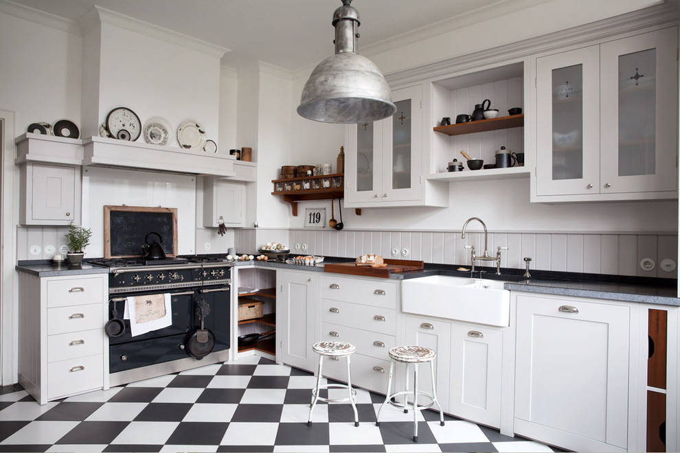 Idée de décoration pour une grande cuisine champêtre en L fermée avec un évier de ferme, un placard à porte shaker, des portes de placard blanches, une crédence grise, un électroménager noir et aucun îlot.