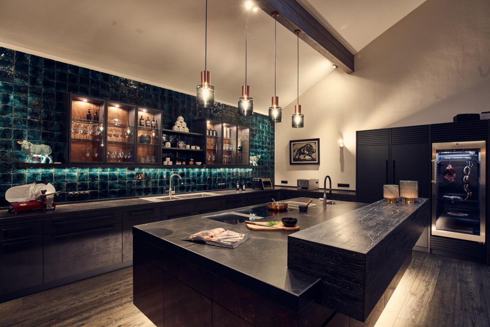 Large urban u-shaped dark wood floor and exposed beam open concept kitchen photo in Munich with an integrated sink, flat-panel cabinets, green backsplash, subway tile backsplash, an island and black countertops