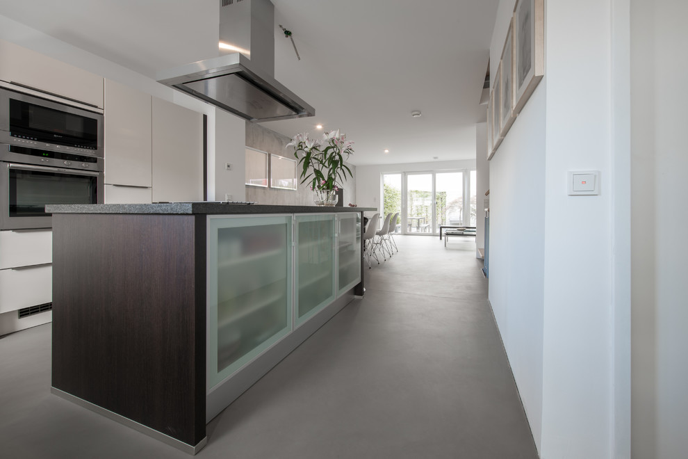 Offene, Geräumige Industrial Küche in L-Form mit Betonboden, grauem Boden und Kücheninsel in Köln