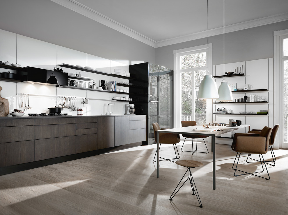 Einzeilige, Große Moderne Wohnküche ohne Insel mit flächenbündigen Schrankfronten, dunklen Holzschränken, Küchenrückwand in Weiß und hellem Holzboden in München