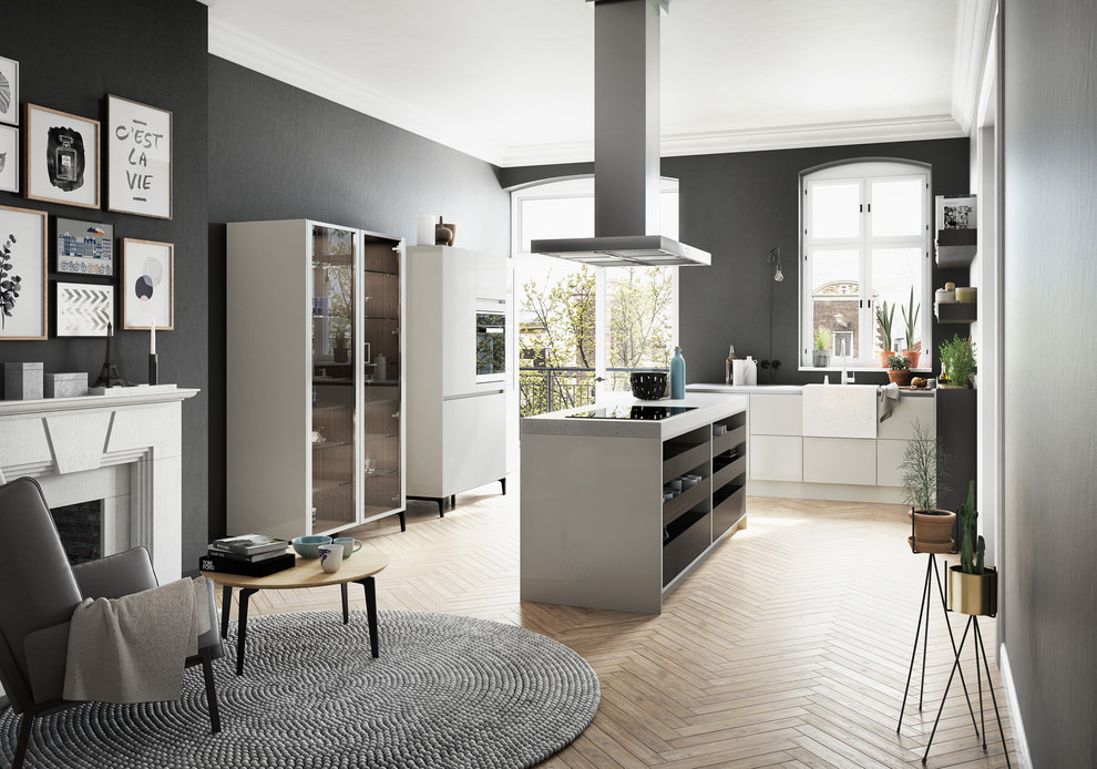 Große Moderne Wohnküche in L-Form mit hellem Holzboden, Kücheninsel, beigen Schränken, Mineralwerkstoff-Arbeitsplatte und Küchenrückwand in Schwarz in München