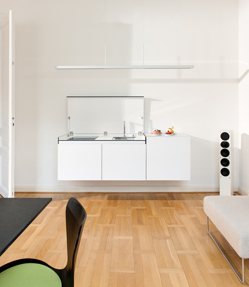 Aménagement d'une petite cuisine contemporaine avec des portes de placard blanches et une crédence blanche.