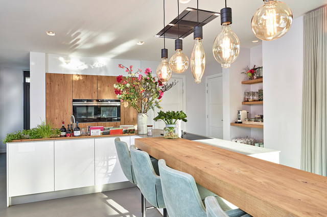 Sonnige Küche mit L-förmiger Insel in Hochglanzweiß und Bergeiche