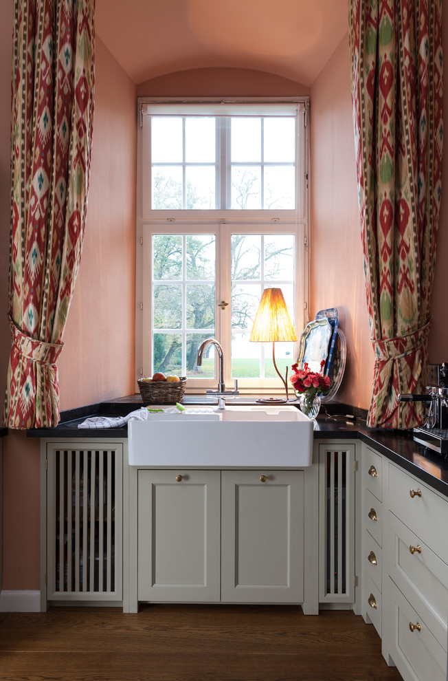 Bild på ett stort lantligt kök, med en rustik diskho, luckor med lamellpanel, beige skåp, granitbänkskiva, rosa stänkskydd, stänkskydd i keramik, färgglada vitvaror, mellanmörkt trägolv och en köksö