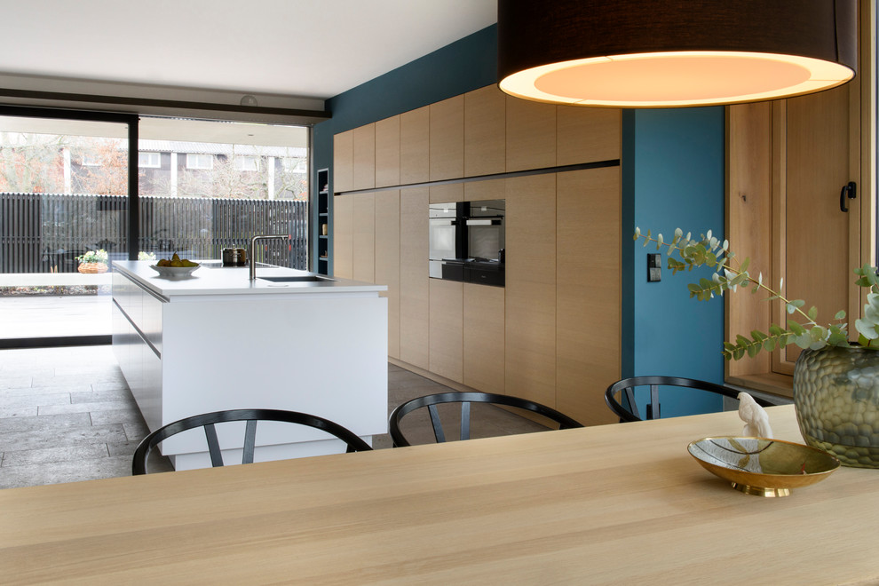 Zweizeilige, Große Moderne Wohnküche mit integriertem Waschbecken, flächenbündigen Schrankfronten, schwarzen Elektrogeräten, Kücheninsel, grauem Boden und weißer Arbeitsplatte in Stuttgart