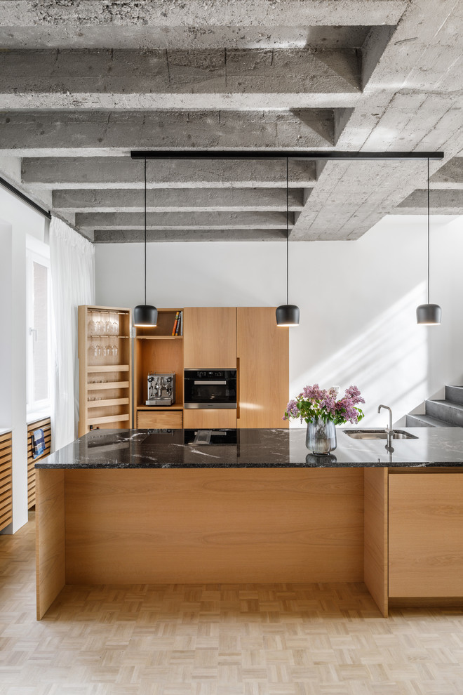 Offene, Zweizeilige Moderne Küche mit flächenbündigen Schrankfronten, hellbraunen Holzschränken, Marmor-Arbeitsplatte, Kücheninsel und schwarzer Arbeitsplatte in Köln