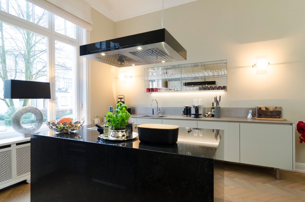 Offene, Zweizeilige, Mittelgroße Moderne Küche mit Einbauwaschbecken, flächenbündigen Schrankfronten, grauen Schränken, braunem Holzboden, zwei Kücheninseln und braunem Boden in Hamburg