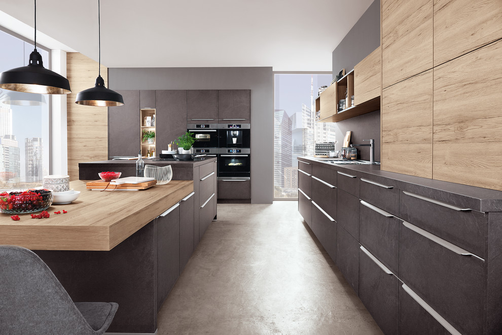 Idee per una cucina minimal con ante lisce, ante grigie, paraspruzzi grigio, elettrodomestici neri, pavimento in cemento, pavimento beige e top grigio