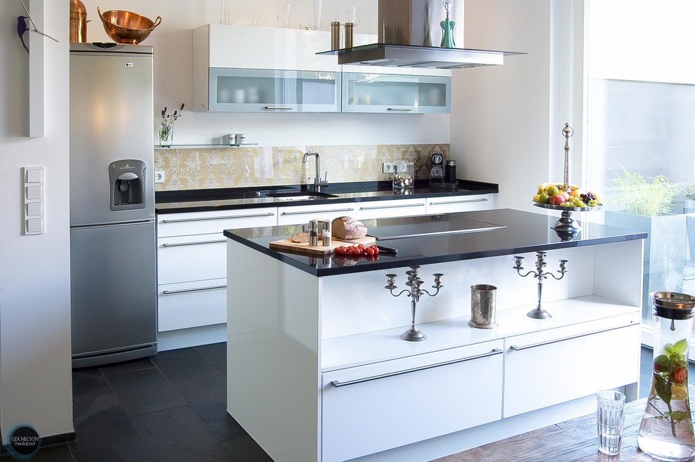 Modern inredning av ett mellanstort linjärt kök med öppen planlösning, med släta luckor, vita skåp, flerfärgad stänkskydd, glaspanel som stänkskydd, rostfria vitvaror, skiffergolv, en köksö och en undermonterad diskho