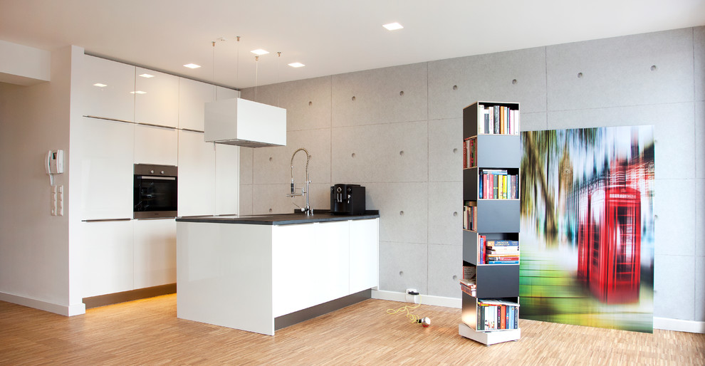 Idee per una piccola cucina ad ambiente unico minimalista con ante lisce, ante bianche, elettrodomestici in acciaio inossidabile, penisola e pavimento in legno massello medio