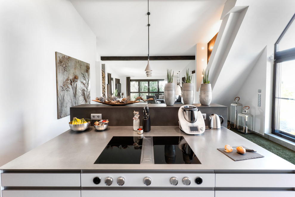 Offene, Mittelgroße Moderne Küche mit flächenbündigen Schrankfronten, weißen Schränken, schwarzen Elektrogeräten, Kücheninsel und grauer Arbeitsplatte in Nürnberg
