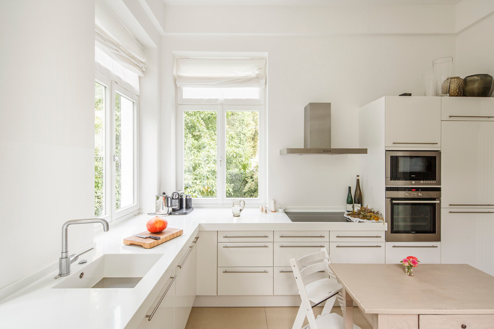Свежая идея для дизайна: большая угловая кухня в современном стиле с плоскими фасадами, белыми фасадами, обеденным столом, монолитной мойкой и окном - отличное фото интерьера