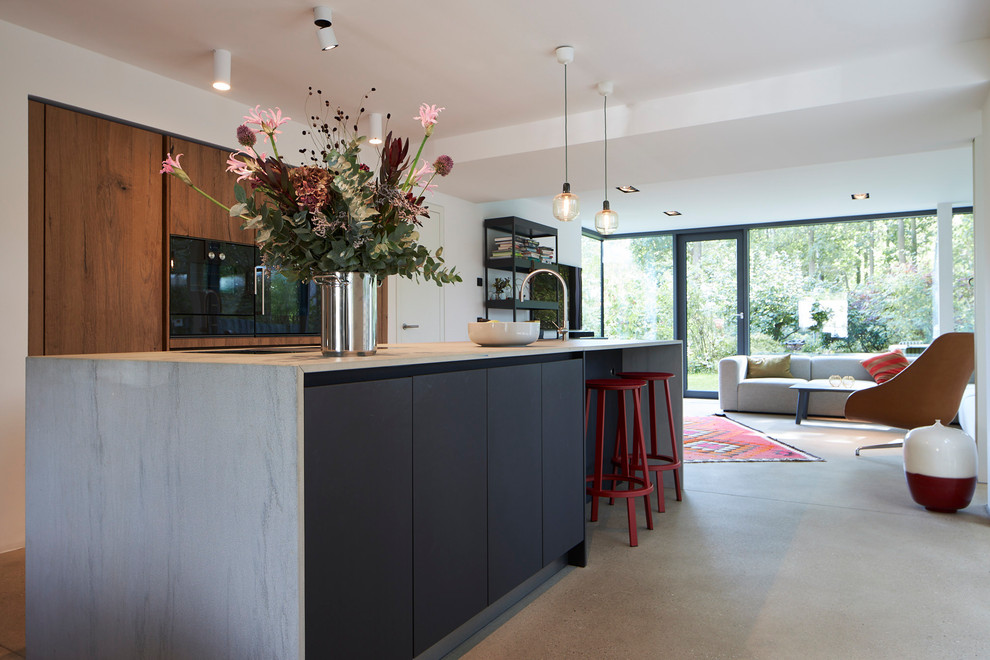 Immagine di un cucina con isola centrale minimalista con ante lisce, ante in legno bruno, top in quarzite, pavimento in cemento, pavimento grigio e top grigio