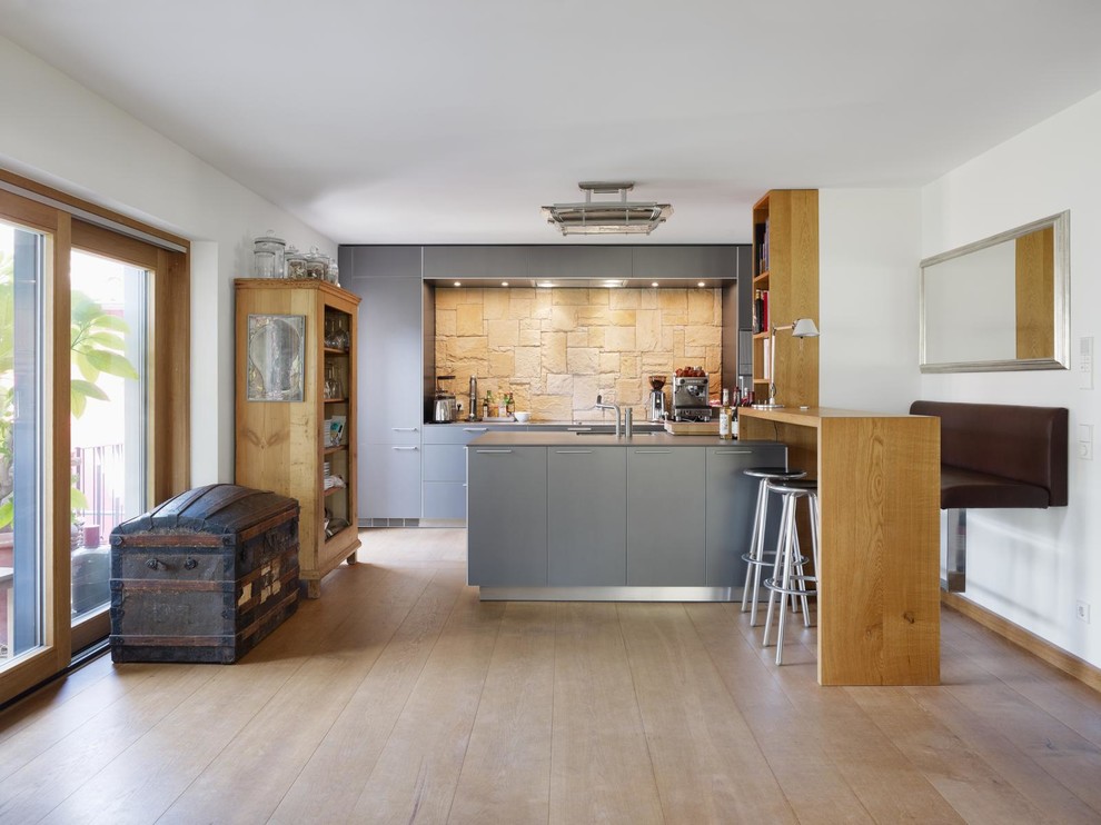 Exempel på ett modernt kök, med en integrerad diskho, släta luckor, grå skåp, bänkskiva i koppar, beige stänkskydd, rostfria vitvaror, mellanmörkt trägolv och en halv köksö