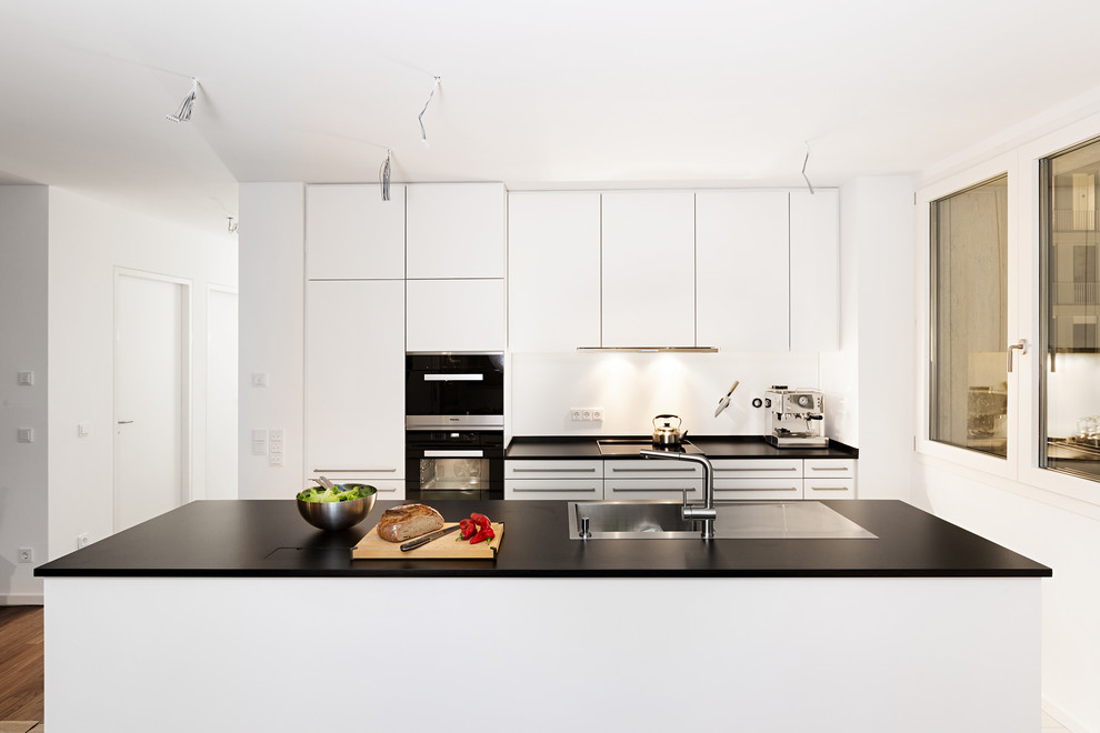 Idee per una cucina minimal di medie dimensioni con ante lisce, ante bianche, top in laminato, paraspruzzi in legno, elettrodomestici in acciaio inossidabile e paraspruzzi bianco