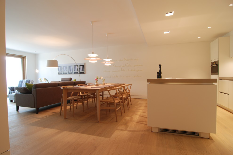 Стильный дизайн: большая параллельная кухня в современном стиле с обеденным столом, плоскими фасадами, белыми фасадами, белым фартуком, светлым паркетным полом и островом - последний тренд