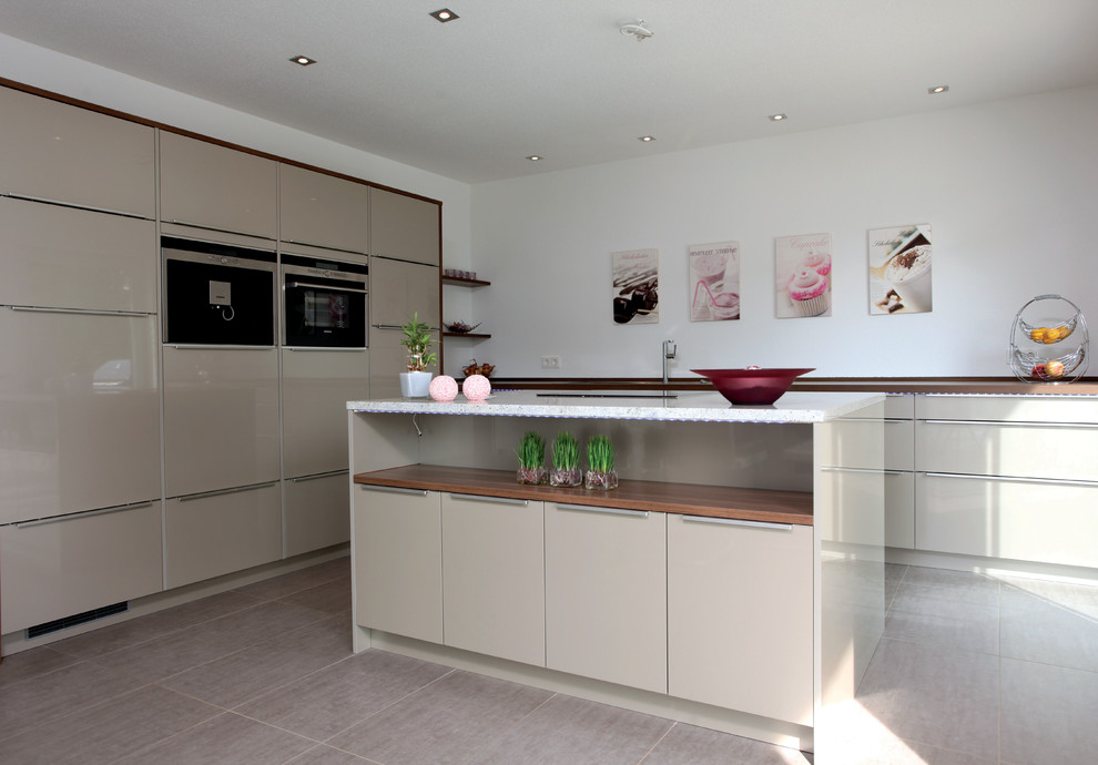 Offene Moderne Küche mit beigen Schränken, Küchenrückwand in Weiß und braunem Boden in Sonstige