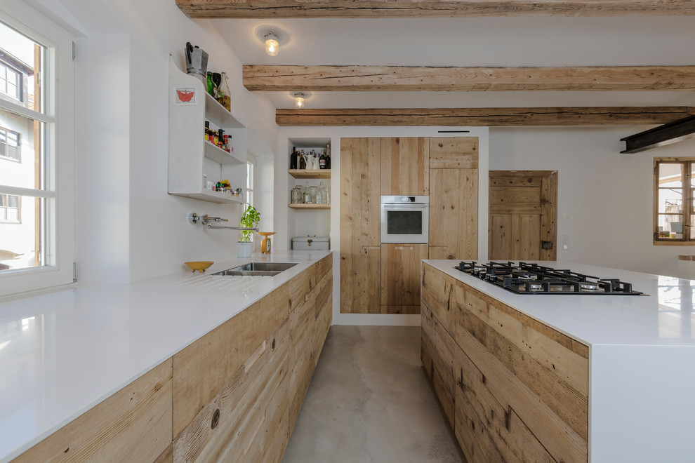 Esempio di una grande cucina industriale con lavello sottopiano, ante lisce, ante in legno chiaro, top in superficie solida e pavimento in cemento