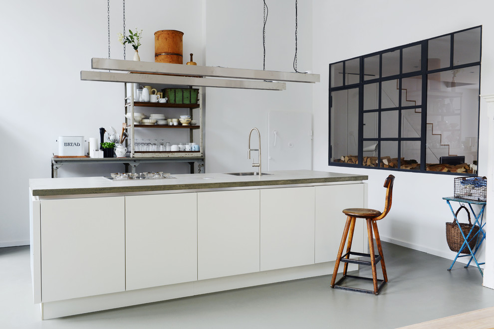 Offene, Kleine Industrial Küche mit weißen Schränken, Kücheninsel, Einbauwaschbecken, Küchenrückwand in Weiß und flächenbündigen Schrankfronten in Berlin