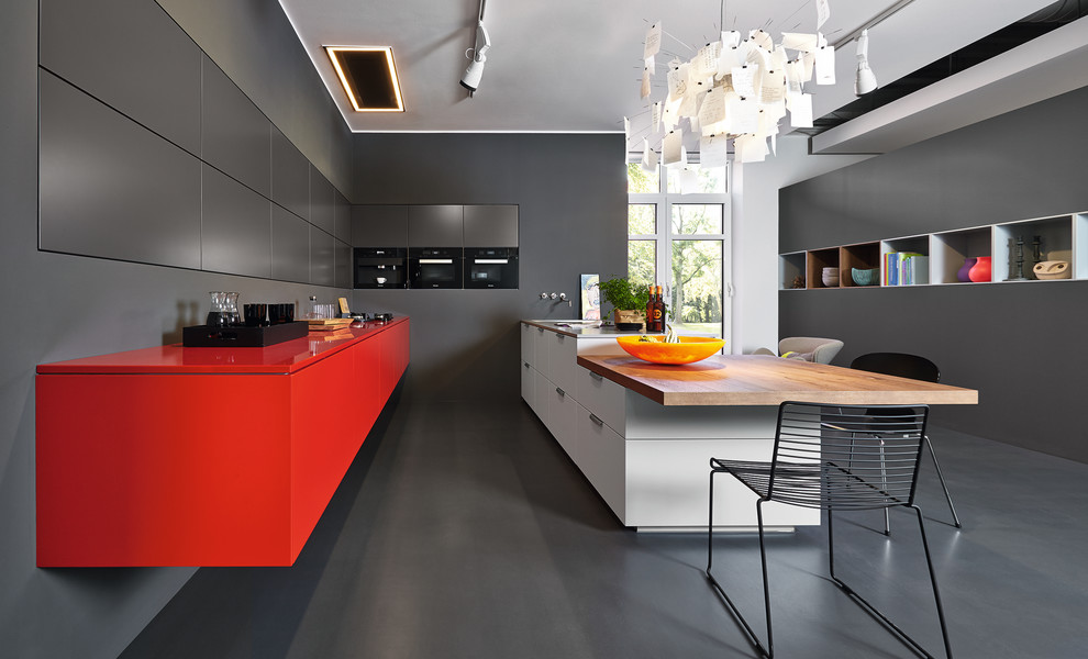 Moderne Wohnküche mit flächenbündigen Schrankfronten, roten Schränken, schwarzen Elektrogeräten und Halbinsel in Sonstige