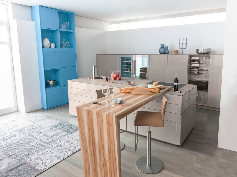 Große Moderne Küche mit Waschbecken, flächenbündigen Schrankfronten, braunen Schränken, Elektrogeräten mit Frontblende, braunem Holzboden und Kücheninsel in Sonstige