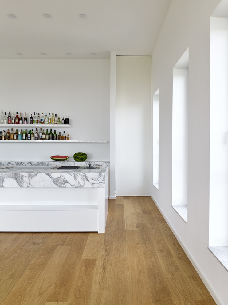 Idéer för ett modernt kök, med en integrerad diskho, vita skåp, marmorbänkskiva, rostfria vitvaror, mellanmörkt trägolv och en köksö